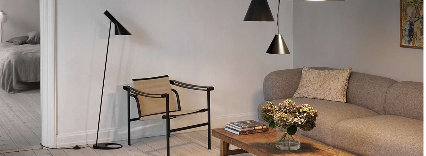 aj stehleuchte schwarz neben einem sessel