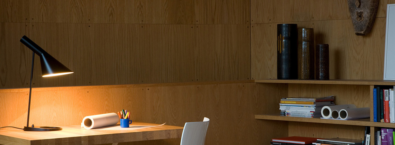 aj tischleuchte auf einem schreibtisch aus holz in einem stilvollen arbeitszimmer