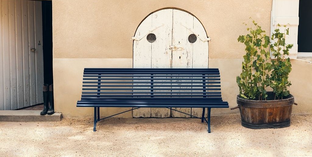 Tolle blaue premium Parkbank vor einer beigen Wand 