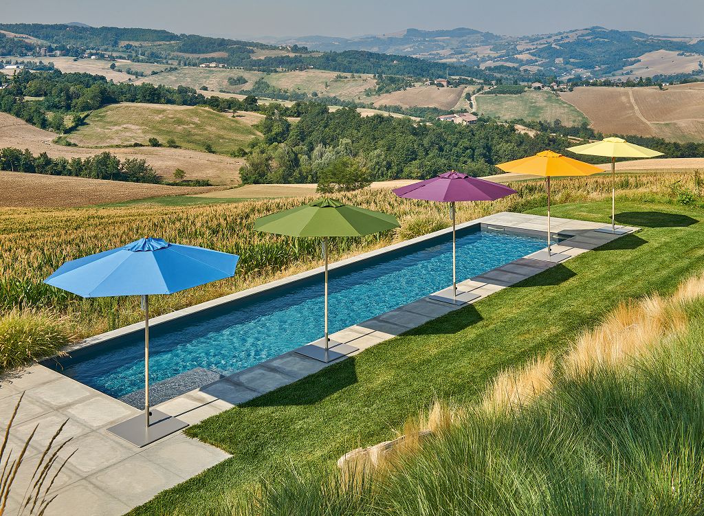 Fünf Premium Gastroschirme in verschiedenen Farben neben einem langen Pool
