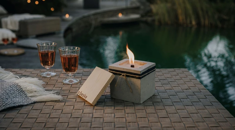 Rechteckiges Beske Betonfeuer vor einem Teich mit zwei gefüllten Gläsern daneben