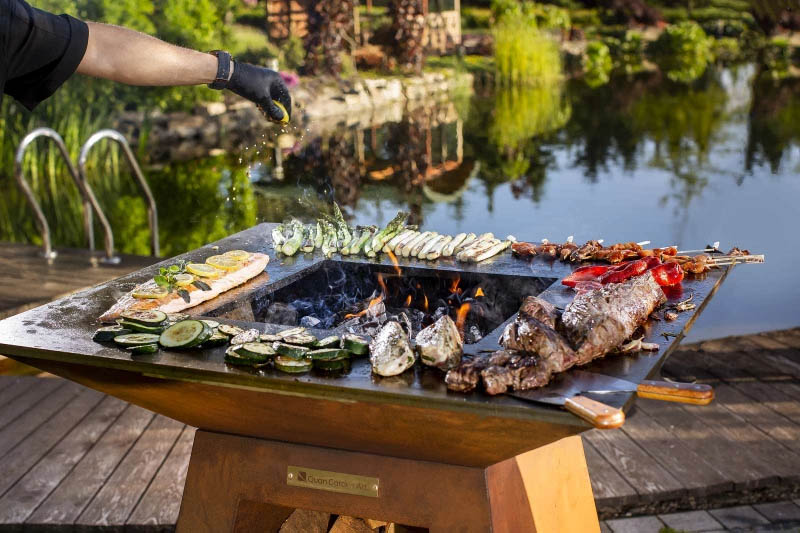 Outdoor Grill mit Plancha von Quan Garden Art, auf dem gerade eine Vielzahl von Lebensmitteln garen