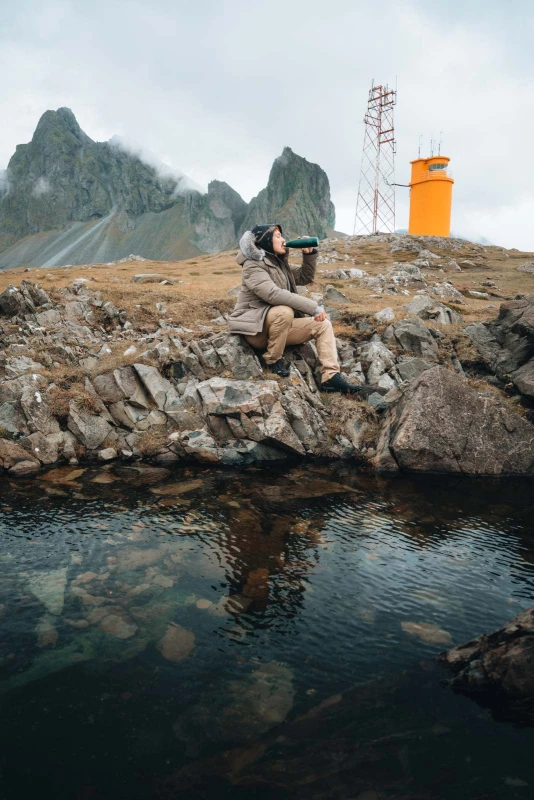 Chilly`s Thermosflasche Mensch sitzt am Wasser und trinkt aus einer Chilly`s Thermosflasche