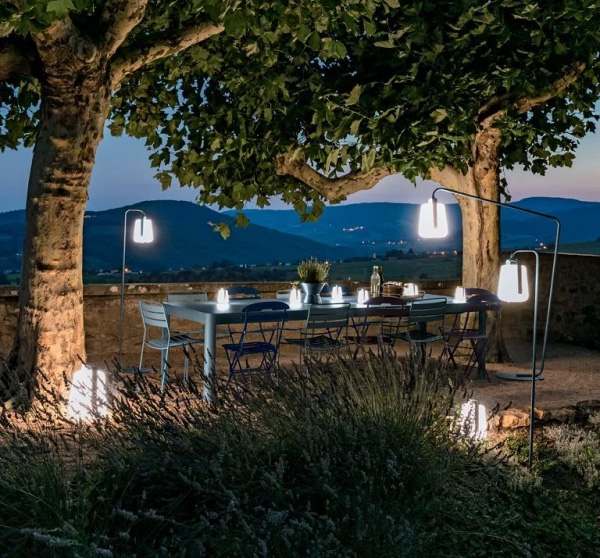 Schöner langer Gastro Outdoor Tisch mit hübscher Beleuchtung unter Bäumen