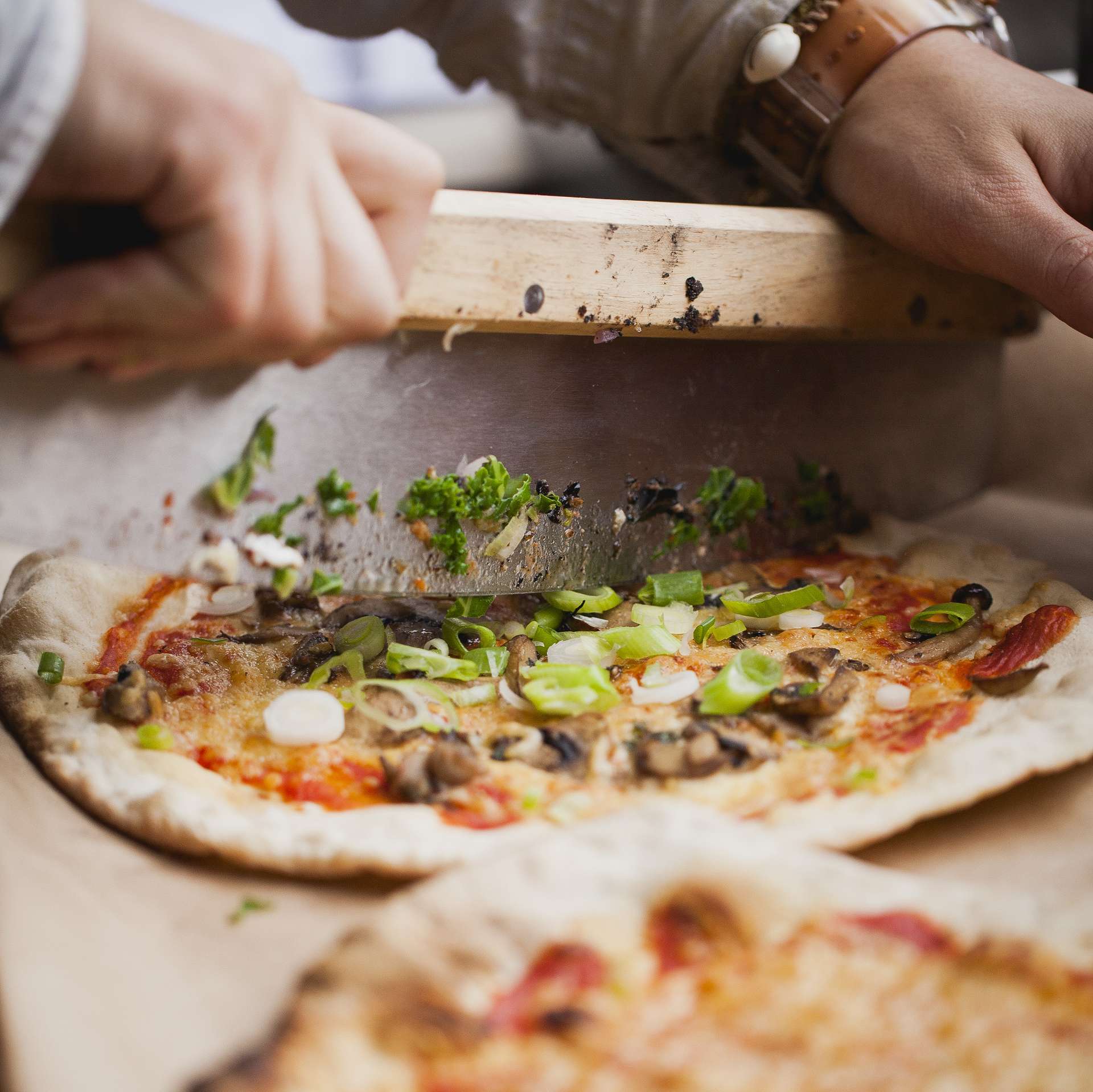 Ein Städler Made Pizzamesser wird dazu benutzt eine frische Pizza zu schneiden
