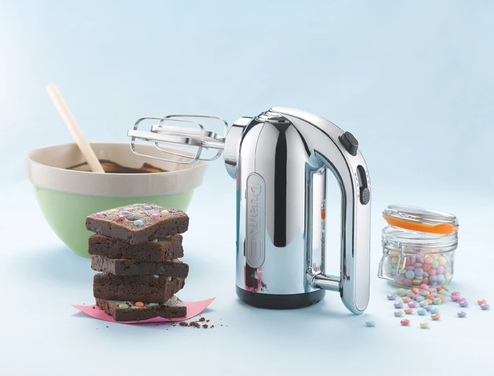 Dualit Premium Handmixer Chrom Premium Handmixer aus Chrom der Marke Dualit mit allerlei Süßigkeiten daneben