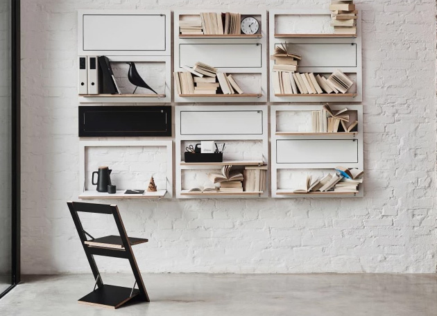 Wohnwand aus Platzsparenden Designer Möbeln die klappbar sind, und einem schwarzen Klappstuhl davor