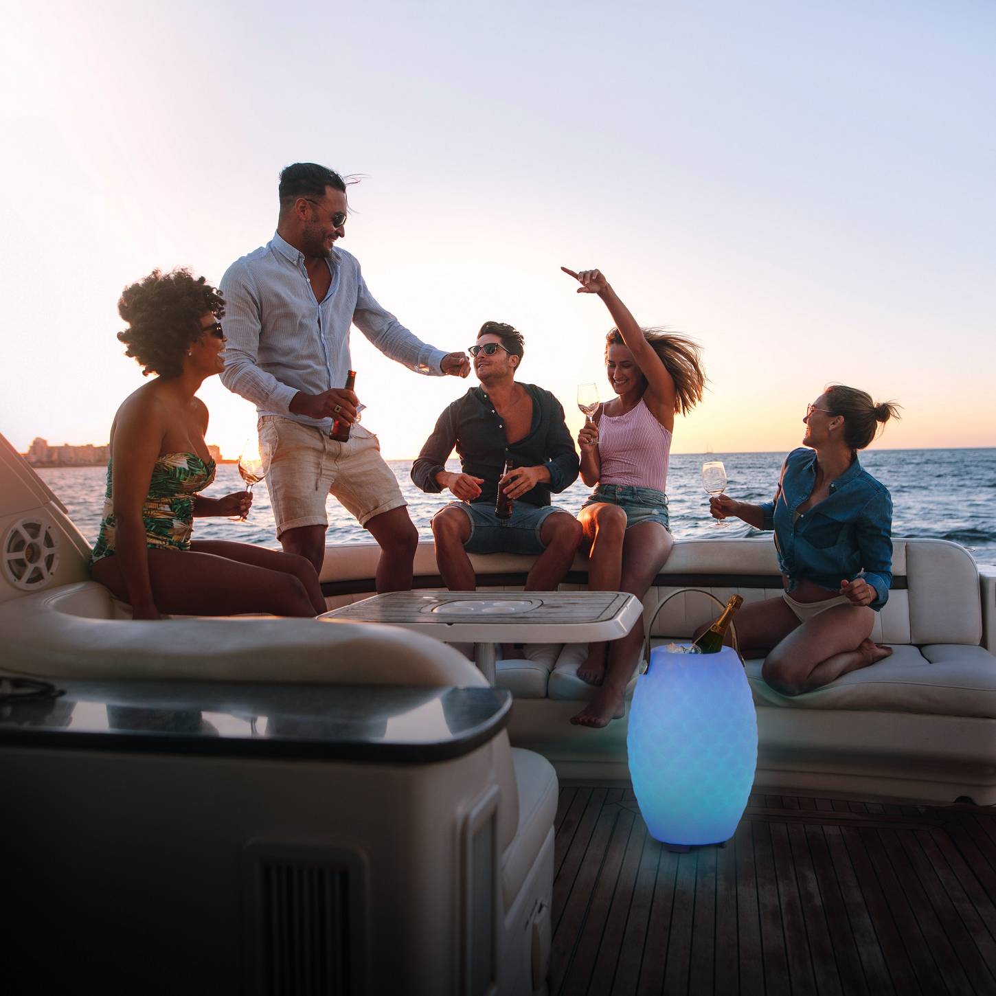 Joouls Outdoor Leuchte The Joouly blau Ausgelassene Menschen auf einer Terrasse mit einer blauen the Joouly Leuchte mit integriertem Lautsprecher von Joouls