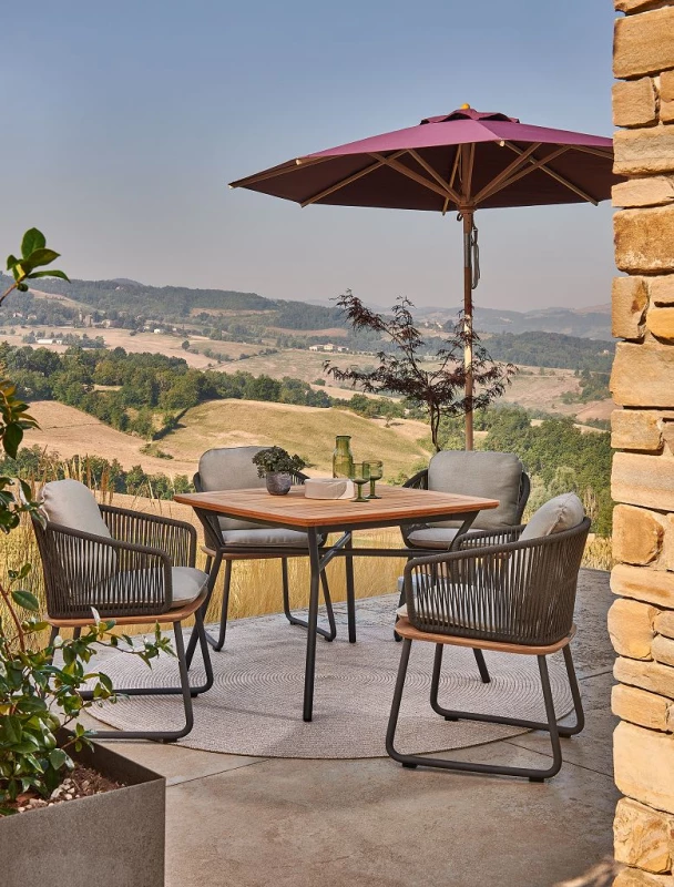 Edle Terrassenstühle mit Tisch für ein Cafe oder ein Restaurant auf einer Terrasse neben einem Sonnenschirm