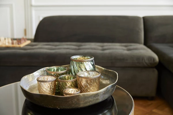 Teelichthalter von Riverdale in einer Metallschale, die auf einem Beistelltisch vor einer Couch steht