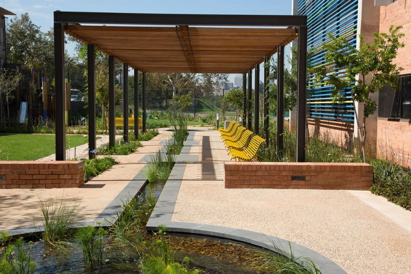 Überdachter Außenbereich einer Grünanlage mit vielen gelben Parkbänken