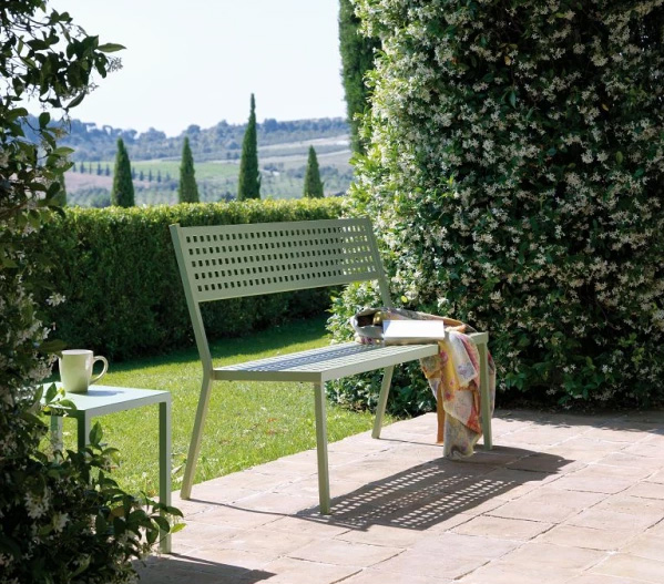 Moderne grüne Parkbank aus Metall neben einer schönen Hecke im Grünen