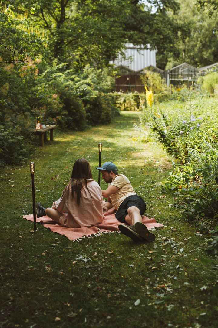 Zwei Weltevree Sticklight Leuchten, die neben einem Pärchen im Boden stecken