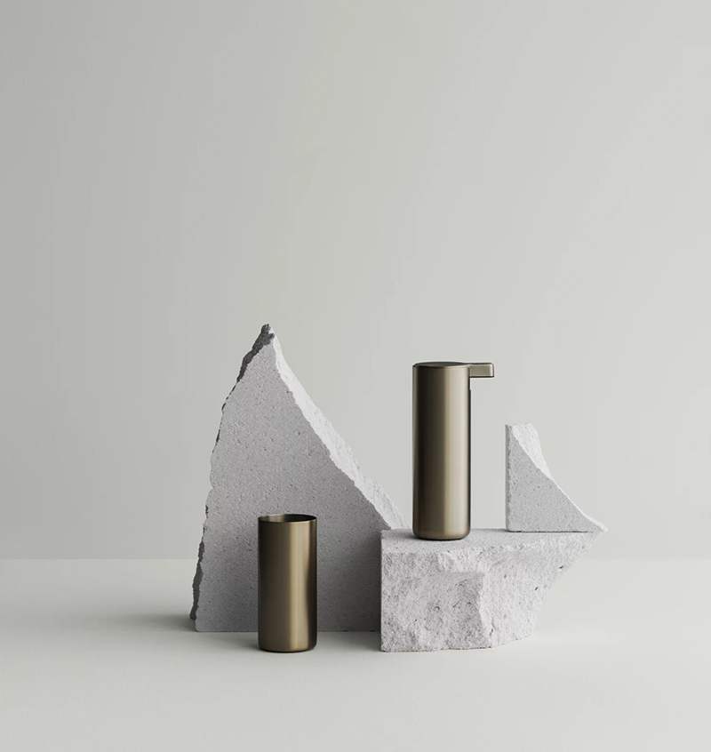 Modo Seifenspender Kupfer Modo Seifenspender und Zahnputzbecher in Kupfer in Szene gesetzt auf Steinen vor einer weißen Wand