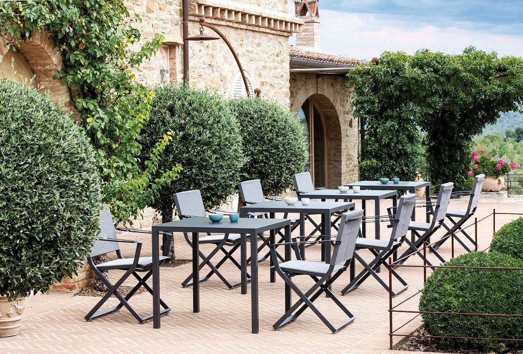 Gastro Outdoor-Tische mit Stühlen auf einer Terrasse vor einem alten Gebäude